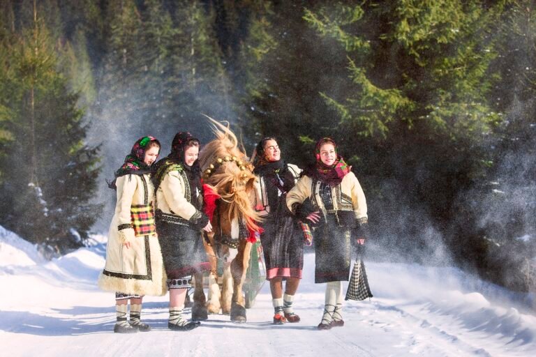 Femei în costume tradiționale românești, pe drum de zăpadă.