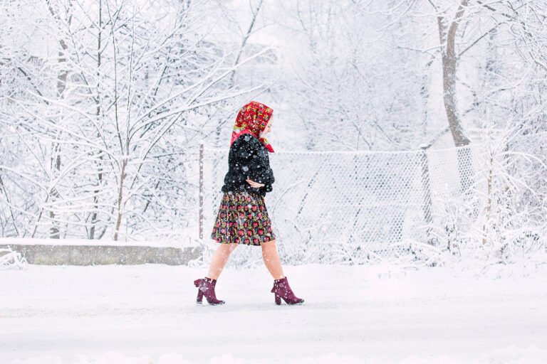 Femeie în zăpadă, îmbrăcată tradițional, iarnă rurală.