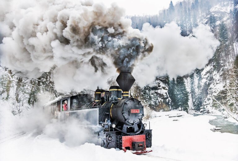 Tren cu aburi în peisaj de iarnă, fumegând.