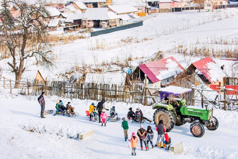 Copii pe sănii trase de tractor, iarnă la țară.