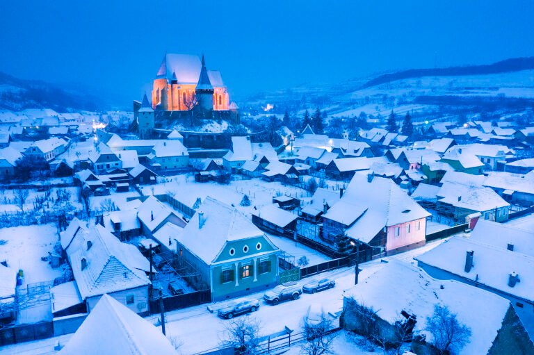 Sat de munte acoperit de zăpadă, noapte liniștită.