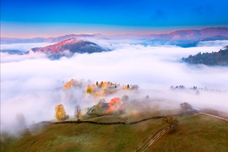 Peisaj montan cu ceață și culori de toamnă.