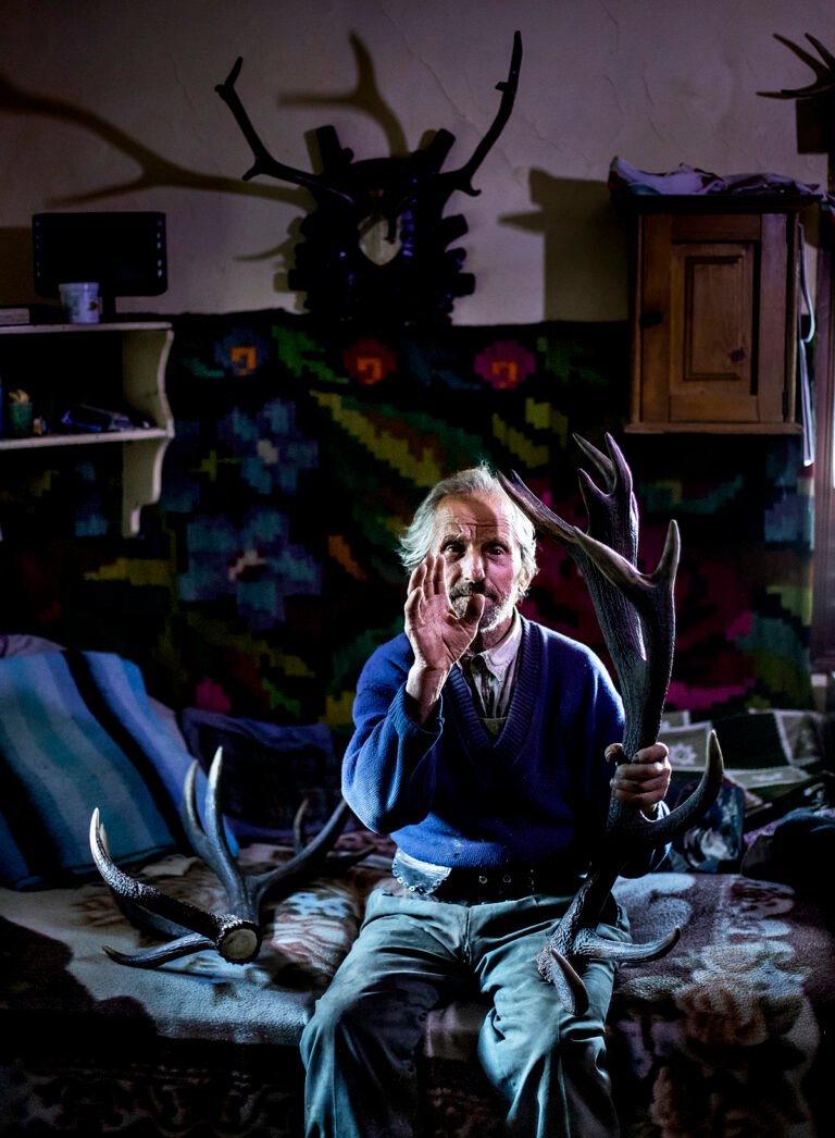 Bărbat cu coarne de cerb în interior rustic.