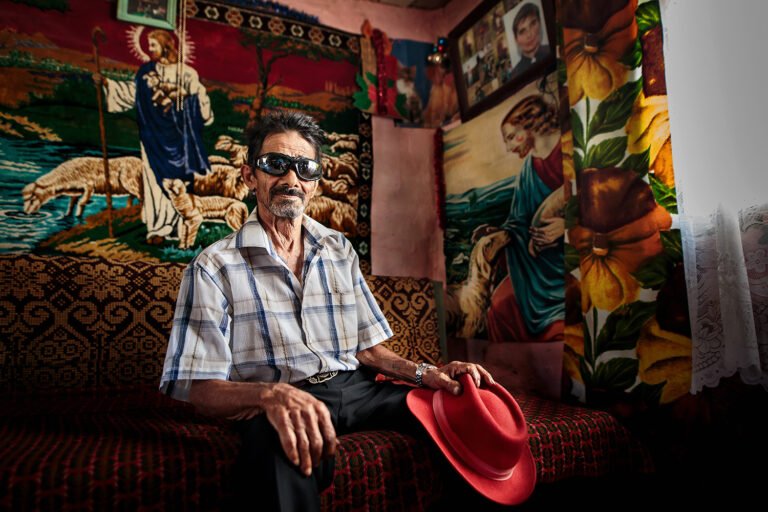 Bărbat cu pălărie roșie într-o cameră decorată.