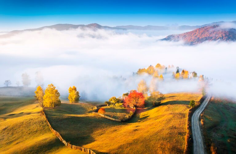 Peisaj montan cu ceață și toamnă colorată.