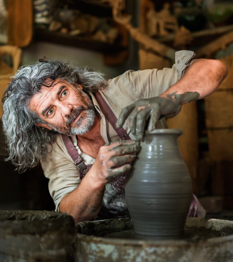 Olar modelând lut pe roata de olărit.