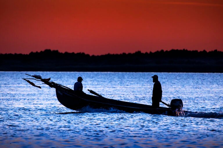 Barcă pe apă la apus, siluete umane