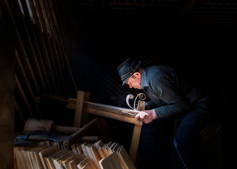 Bătrân tâmplar lucrând în atelierul său tradițional.