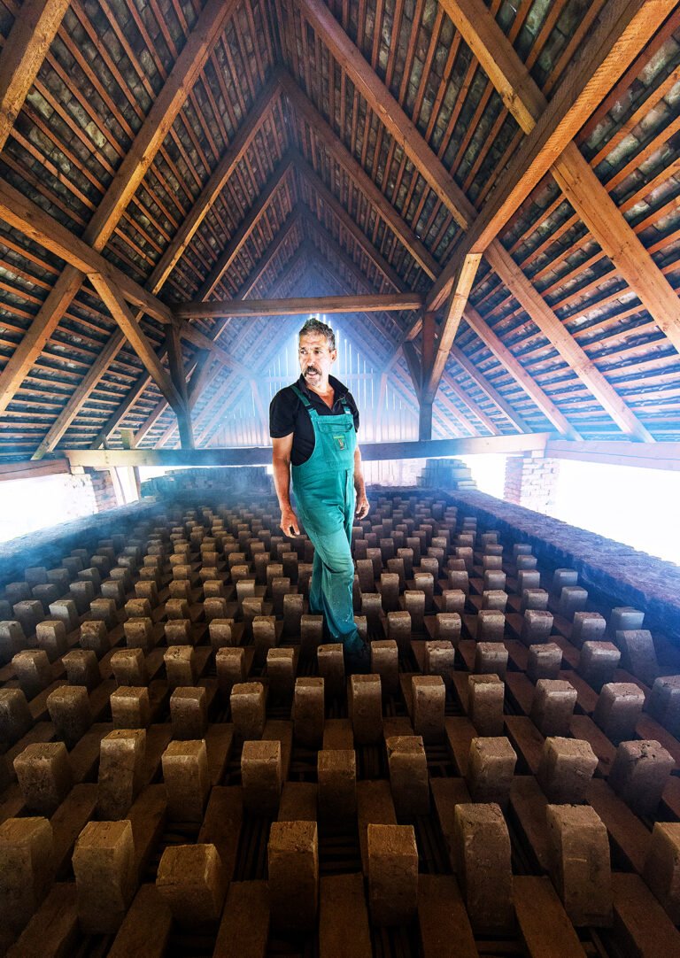 Bărbat în pod, cărămizi depozitate în fundal.