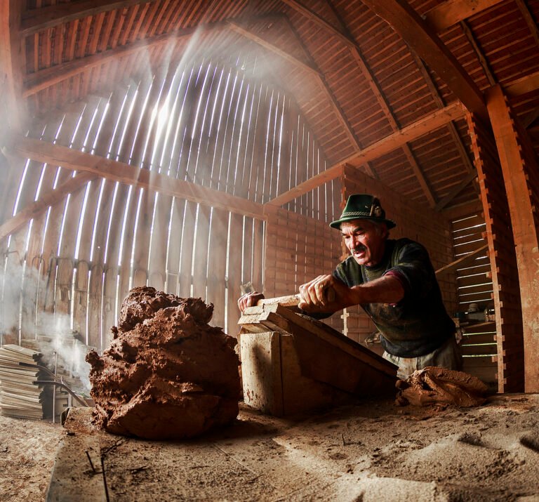 Om lucrând cu lut în hambar din lemn.