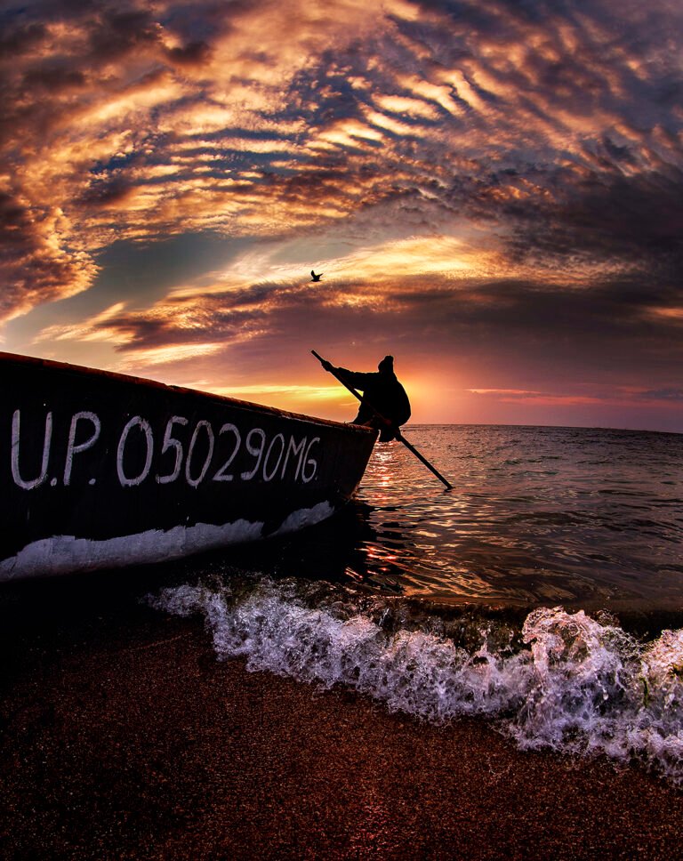 Barcă la apus pe mare, valuri și cer spectaculos.