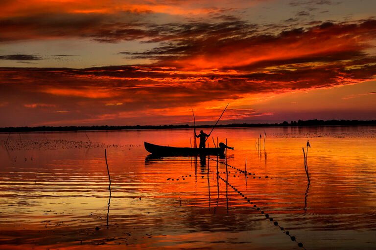 Pescari în barcă la apus de soare