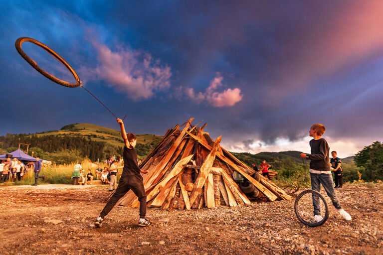 Copii se joacă lângă foc în aer liber.