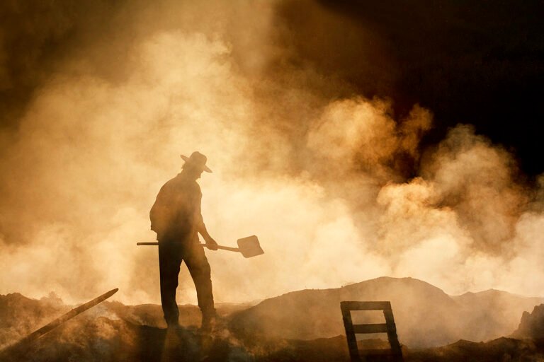 Siluetă om cu lopată în fum dens